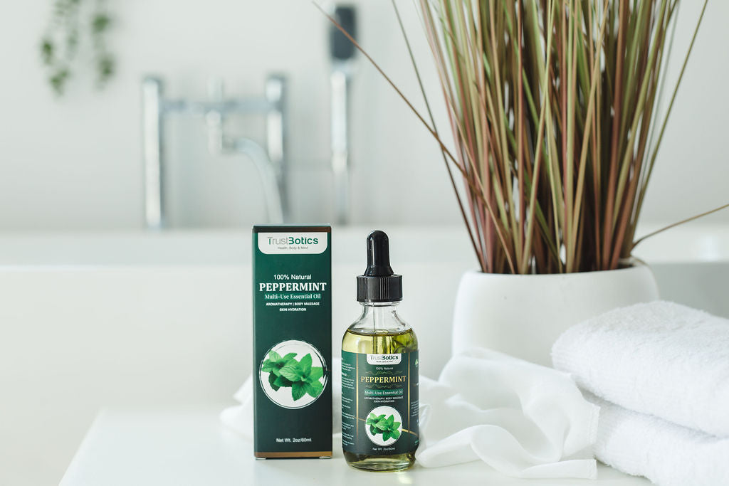 TrustBotics Peppermint Essential Oil bottle with box, placed in a spa-like setting with towels and reed diffuser, evoking freshness and relaxation.