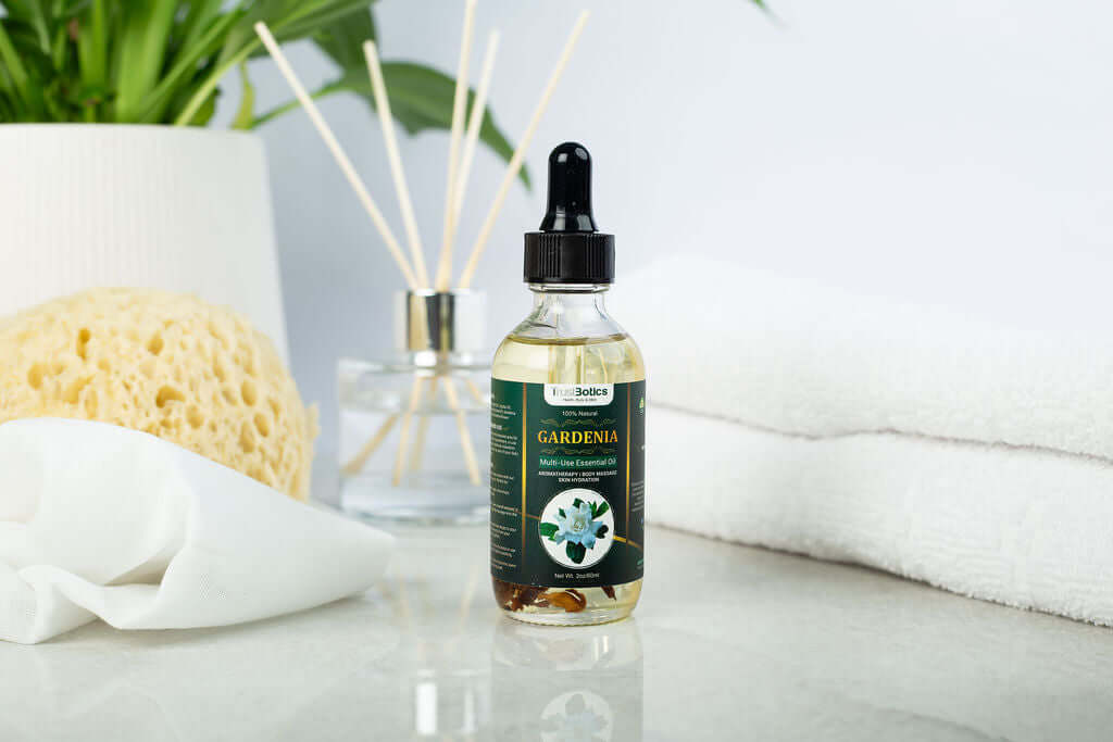 TrustBotics Gardenia Essential Oil bottle on a spa-inspired surface with diffuser, towel, and plant – luxurious floral oil for skincare and aromatherapy.
