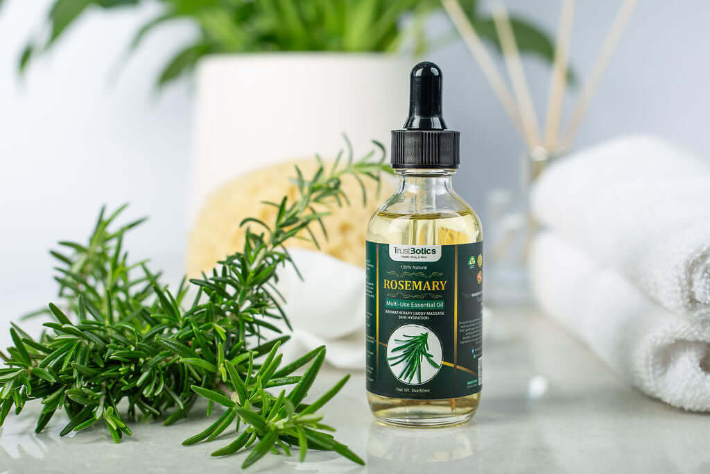 TrustBotics Rosemary Essential Oil bottle surrounded by fresh rosemary sprigs, spa towels, and a calming, natural background.