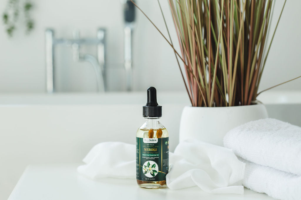 TrustBotics Neroli Essential Oil bottle in modern bathroom setting with white towels and decorative plant, evoking luxury spa ambiance.