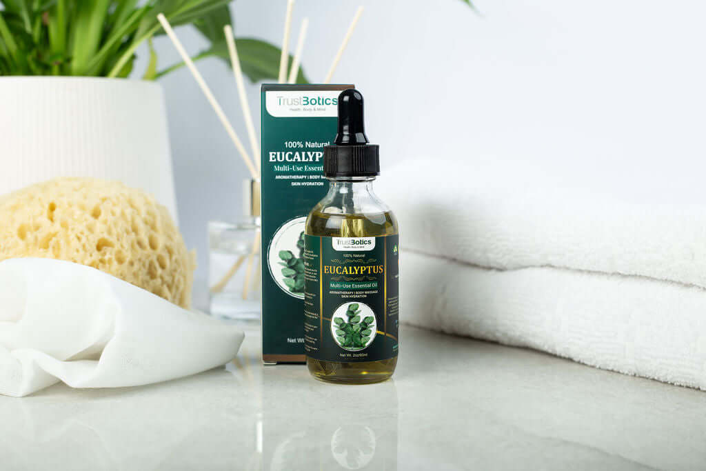 TrustBotics Eucalyptus Multi-Use Essential Oil bottle and box on a spa-inspired background with sponge, diffuser sticks, and white towels, evoking natural freshness and relaxation.
