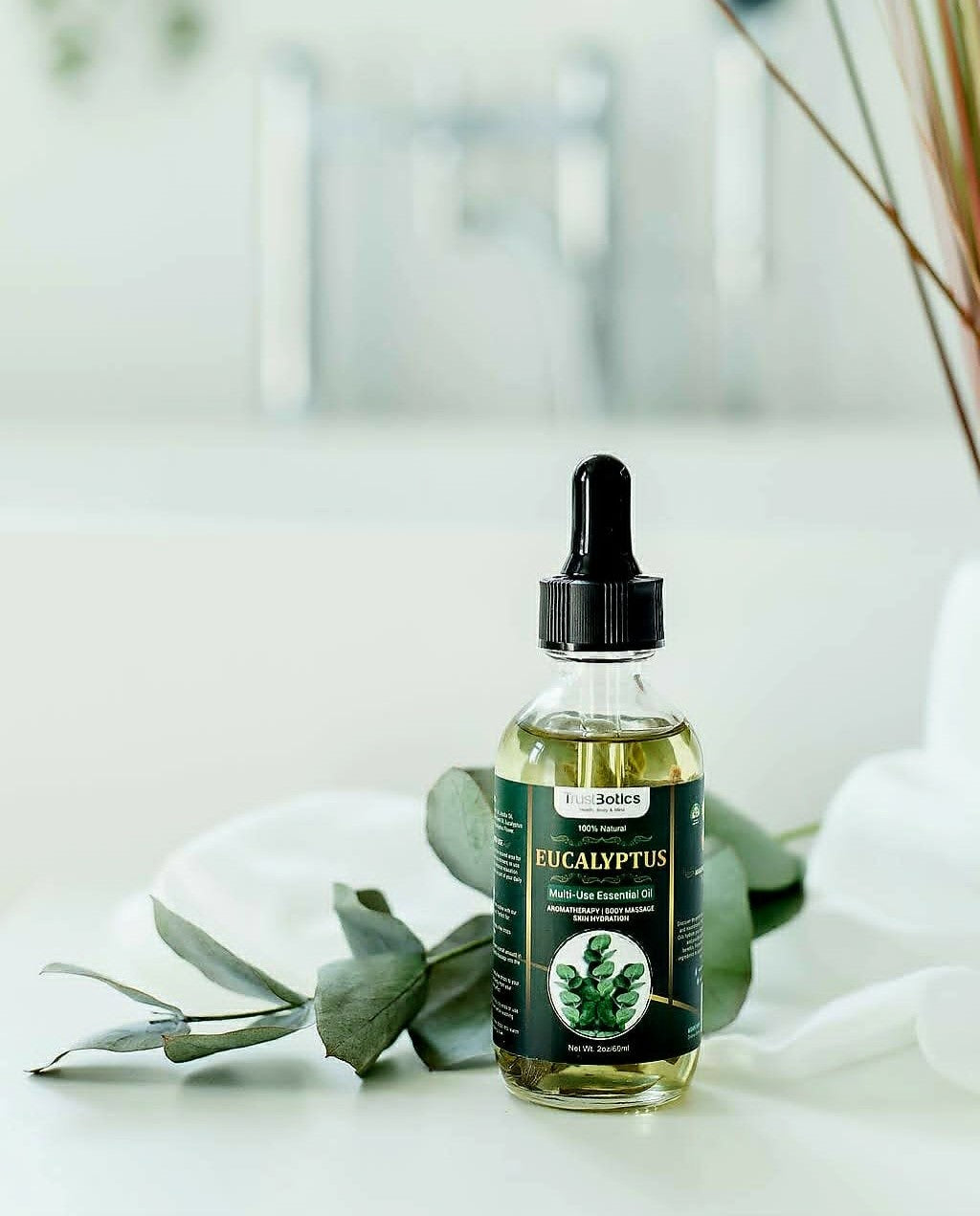 TrustBotics Eucalyptus multi-use essential oil bottle displayed with fresh eucalyptus leaves on a bright background. Ready-to-use luxury aromatherapy oil for daily wellness and self-care rituals.