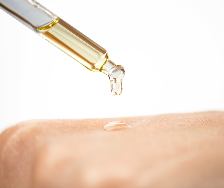 Close up of natural multi-use essential  oil drop from glass pipette applied to skin showing skincare oil texture used in aromatherapy and natural beauty routine
