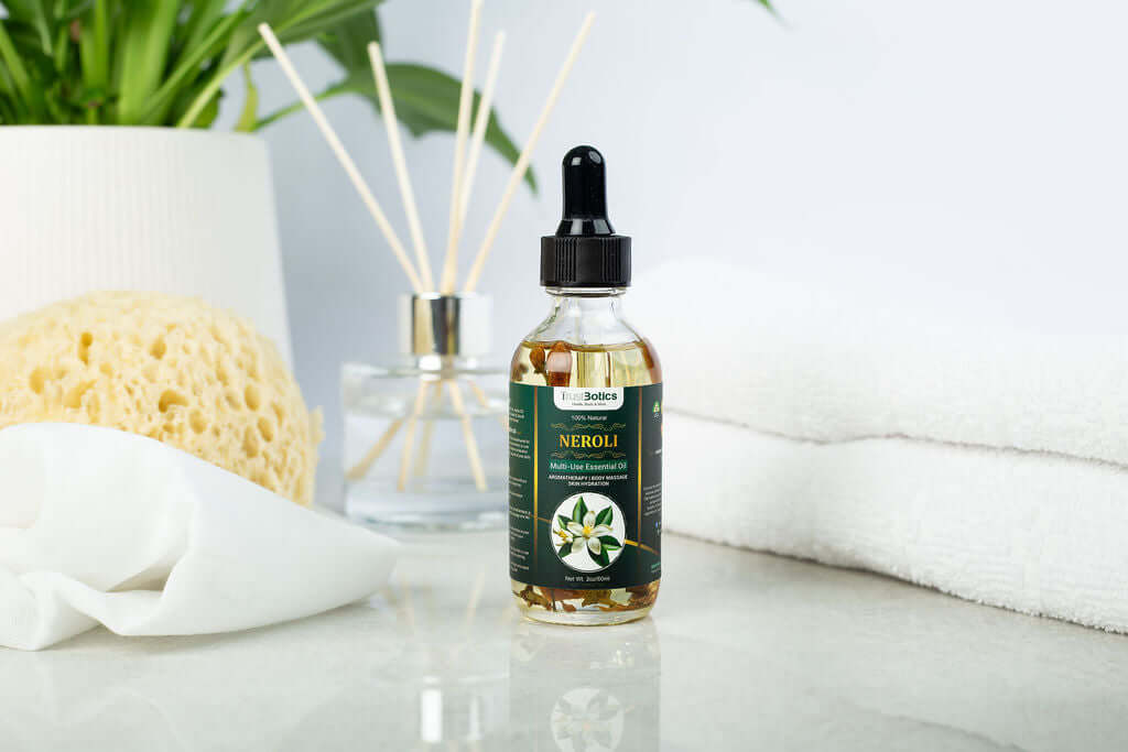 TrustBotics Neroli Multi-Use Essential Oil bottle styled on spa-inspired white surface with natural sponge, green plant, and diffuser sticks, highlighting luxurious self-care.